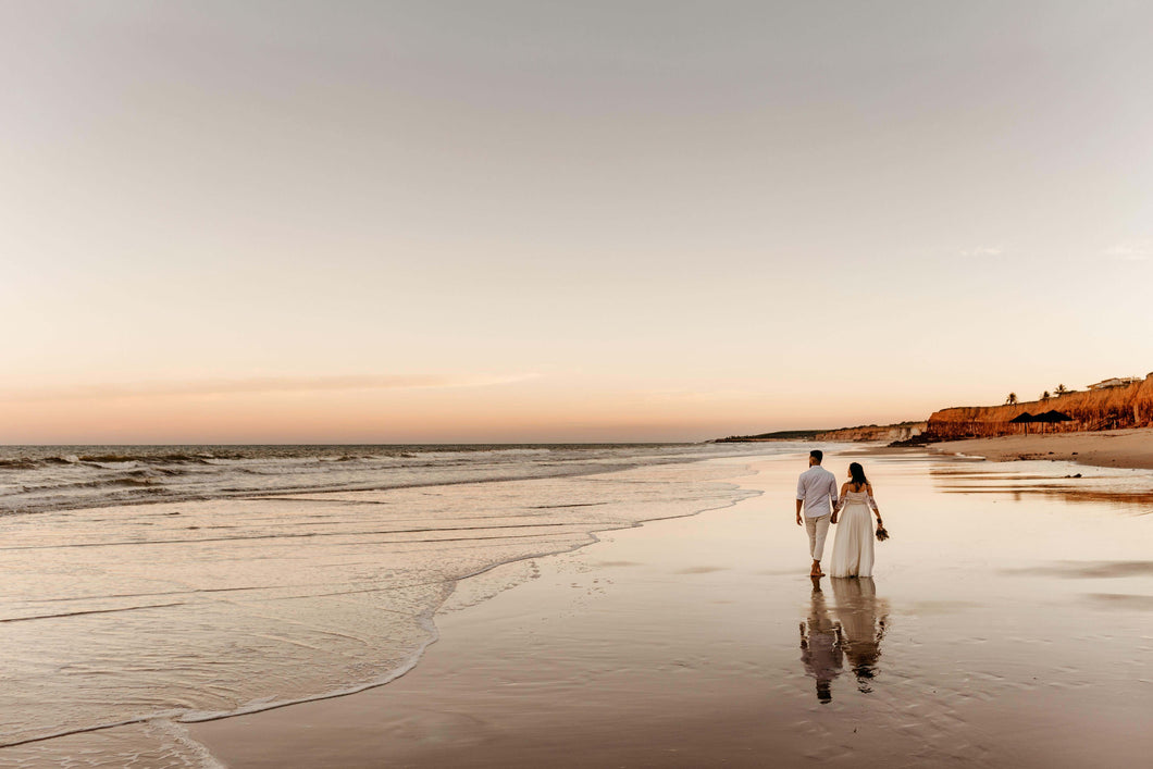 Couple holding hands walking on the beach